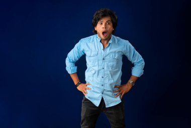 Young handsome man over dark background afraid and shocked with surprise and amazed expression, fear and excited face.