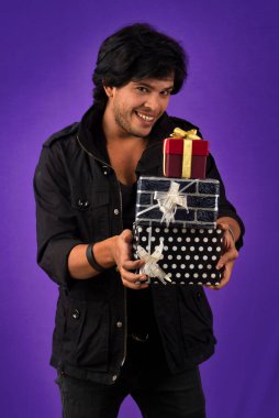 Portrait of young happy smiling handsome man holding gift box on a purple background.