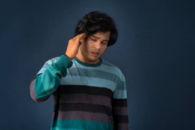 Portrait of young man stress or having the pain of a headache on a grey background.