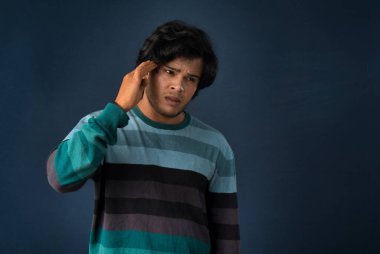 Portrait of young man stress or having the pain of a headache on a grey background.