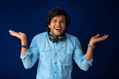 Portrait of a handsome young man enjoying music on headphones on blue background.