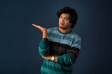 Portrait of a successful cheerful young man pointing and presenting something with hand or finger with a happy smiling face.