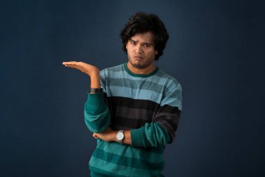 Portrait of a successful cheerful young man pointing and presenting something with hand or finger with a happy smiling face.