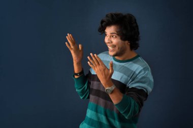 Portrait of a successful cheerful young man pointing and presenting something with hand or finger with a happy smiling face.