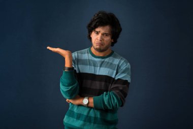 Portrait of a successful cheerful young man holding and presenting something on hand with a happy smiling face.