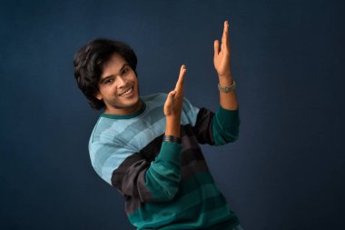 Portrait of a successful cheerful young man pointing and presenting something with hand or finger with a happy smiling face.