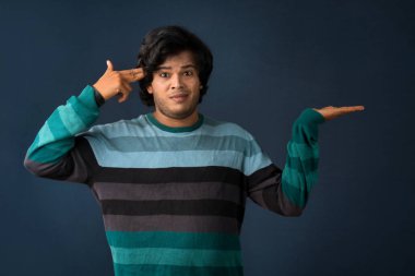 Portrait of a successful cheerful young man holding and presenting something on hand with a happy smiling face.