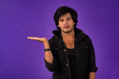 Portrait of a successful cheerful young man holding and presenting something on hand with a happy smiling face.