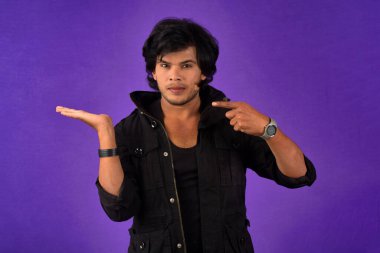 Portrait of a successful cheerful young man holding and presenting something on hand with a happy smiling face.