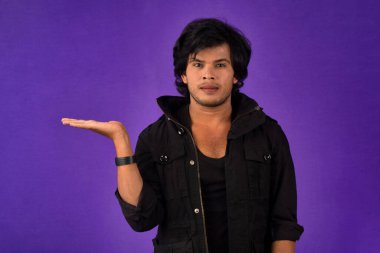 Portrait of a successful cheerful young man holding and presenting something on hand with a happy smiling face.