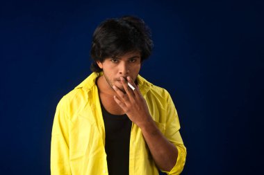 A young man smoking a cigarette and making a lot of smoke around.