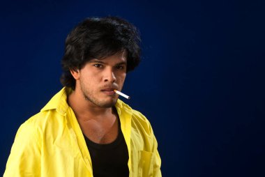 A young man smoking a cigarette and making a lot of smoke around.