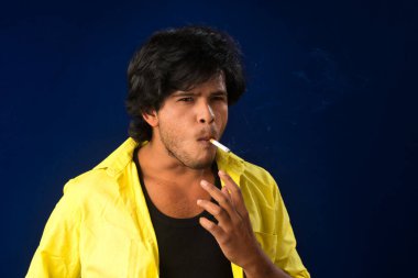 A young man smoking a cigarette and making a lot of smoke around.