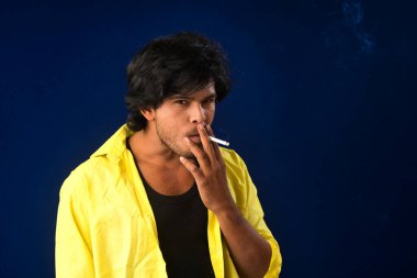 A young man smoking a cigarette and making a lot of smoke around.