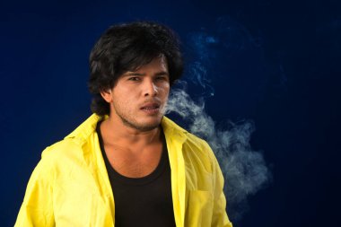 A young man smoking a cigarette and making a lot of smoke around.