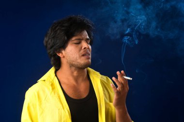 A young man smoking a cigarette and making a lot of smoke around.