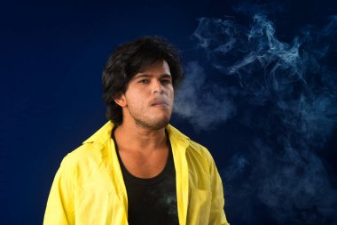 A young man smoking a cigarette and making a lot of smoke around.