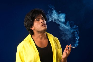 A young man smoking a cigarette and making a lot of smoke around.