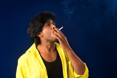 A young man smoking a cigarette and making a lot of smoke around.