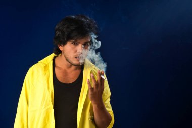 A young man smoking a cigarette and making a lot of smoke around.
