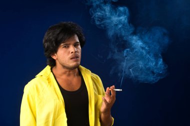 A young man smoking a cigarette and making a lot of smoke around.