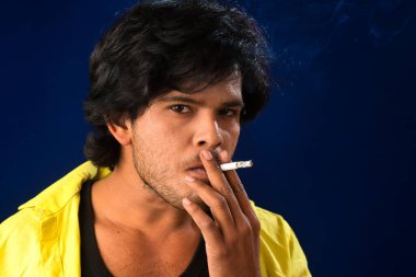 A young man smoking a cigarette and making a lot of smoke around.
