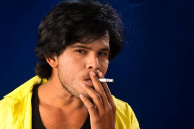 A young man smoking a cigarette and making a lot of smoke around.