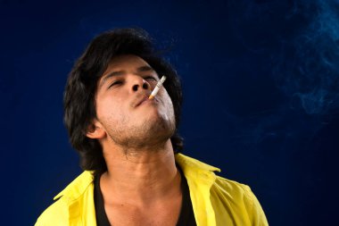 A young man smoking a cigarette and making a lot of smoke around.