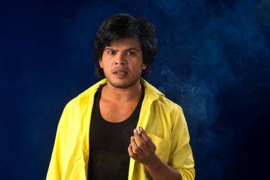 A young man smoking a cigarette and making a lot of smoke around.