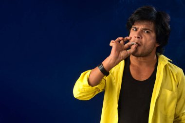 A young man smoking a cigarette and making a lot of smoke around.