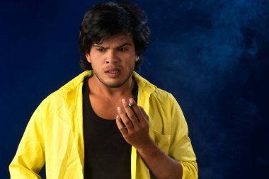 A young man smoking a cigarette and making a lot of smoke around.