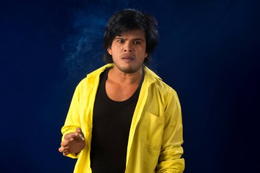 A young man smoking a cigarette and making a lot of smoke around.