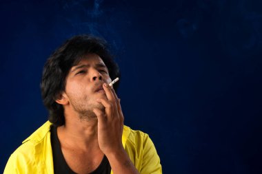 A young man smoking a cigarette and making a lot of smoke around.
