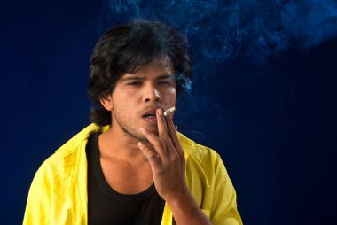 A young man smoking a cigarette and making a lot of smoke around.