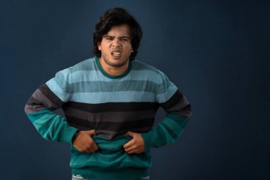 Unhappy man suffering from stomach ache over gray background. People, healthcare, and health problem concept.