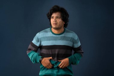Unhappy man suffering from stomach ache over gray background. People, healthcare, and health problem concept.