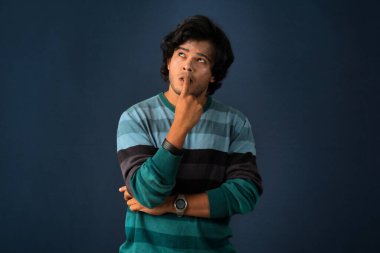 Portrait of a young man thinking on a dark background