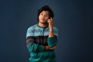 Portrait of a young man thinking on a dark background