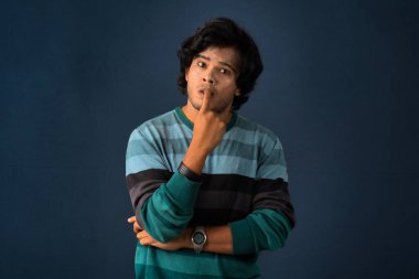 Portrait of a young man thinking on a dark background