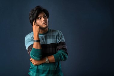 Portrait of a young man thinking on a dark background
