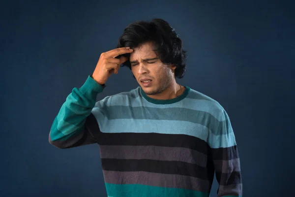 Portrait of young man stress or having the pain of a headache on a grey background.