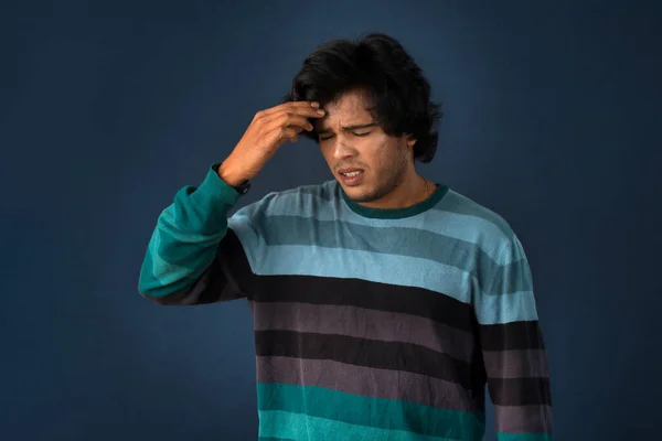 Portrait of young man stress or having the pain of a headache on a grey background.