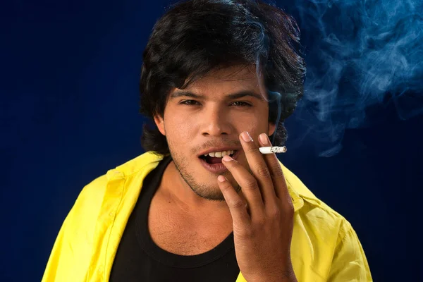 A young man smoking a cigarette and making a lot of smoke around.