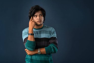 Portrait of a young man thinking on a dark background