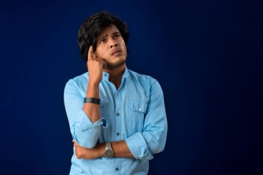 Portrait of a young man thinking on a dark background
