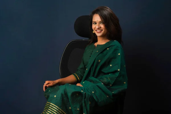 A beautiful girl sitting on an executive chair and posing.