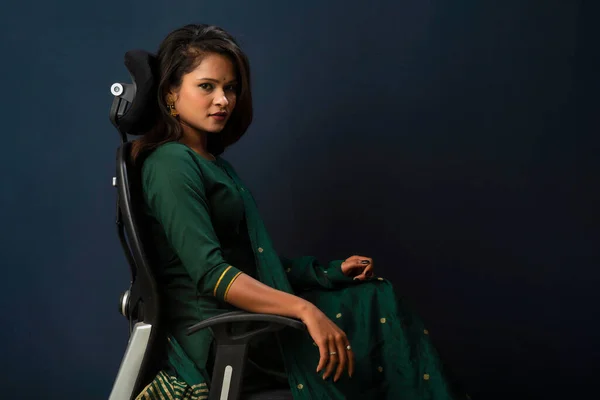 A beautiful girl sitting on an executive chair and posing.