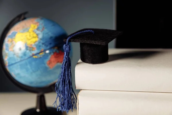 Global education concept. Graduation hat on books and globe