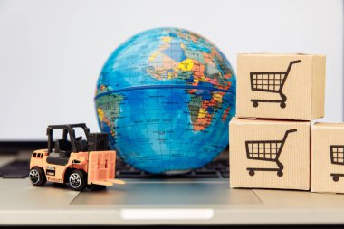 Yakın plan dizüstü bilgisayarında kutuları olan bir dünya. Çevrimiçi alışveriş ve dağıtım kavramı