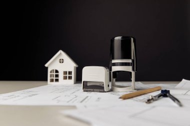 Modeli ev, gözlük ve pullu gri bir masa.